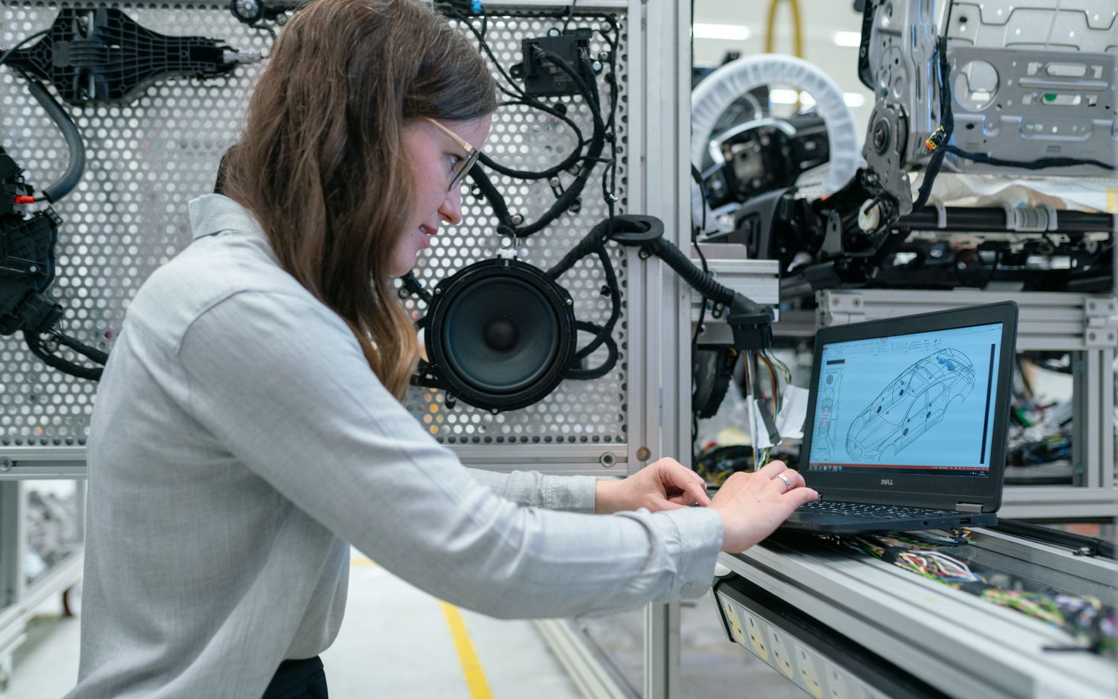 Woman conducting engineering research in a sound system workshop using a laptop.