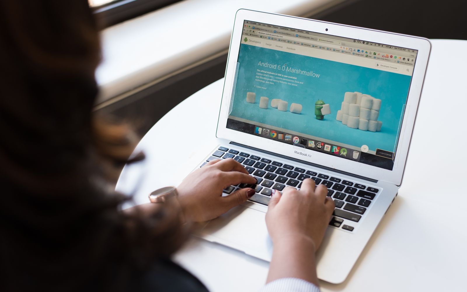 Businesswoman working on laptop with Android 6.0 Marshmallow webpage open.