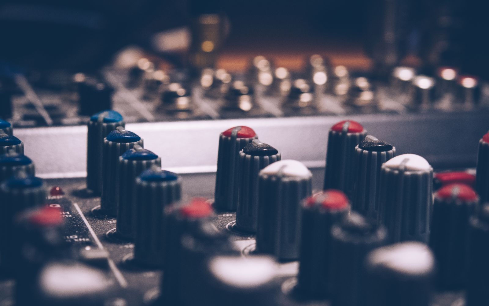 Close-up of audio mixer knobs in a dimly lit studio. Perfect for music and technology themes.