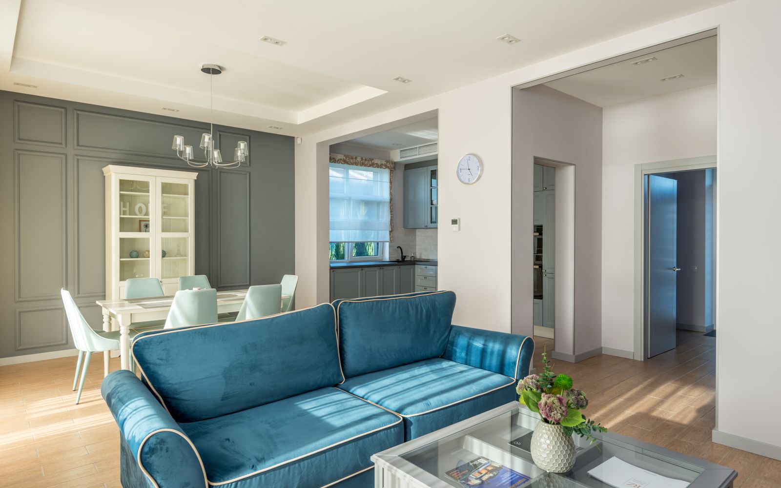 Bright modern living room featuring blue sofa, dining table, and elegant decor.